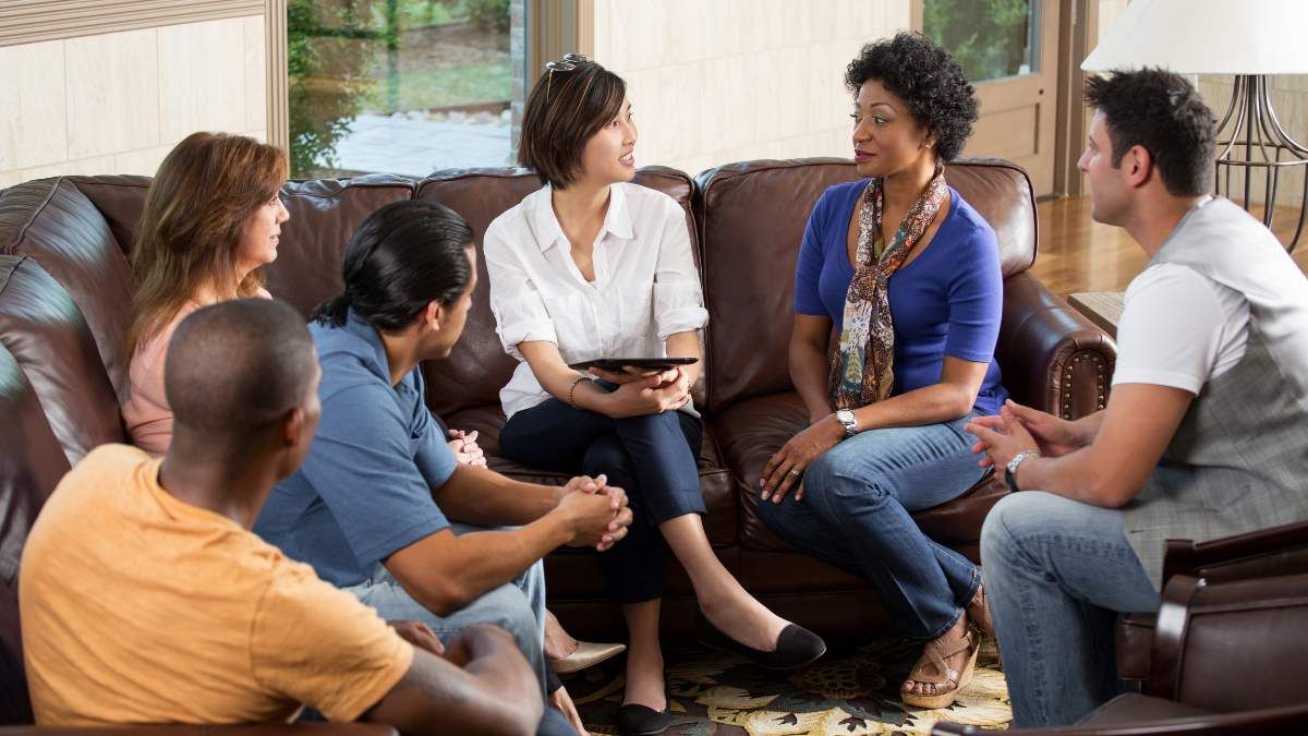 Interventionist having a meeting with support circle in a living room